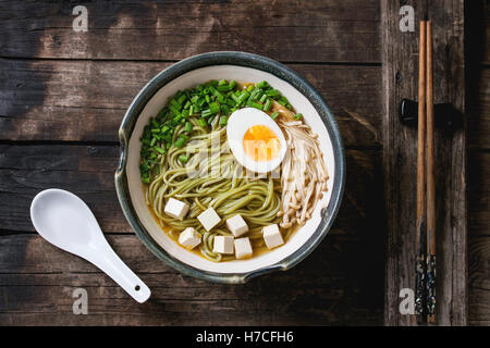 Bol de soupe de style asiatique avec des nouilles soba au thé vert, oeuf, champignons, petits oignons et le tofu, fromage servi avec des baguettes et w Banque D'Images