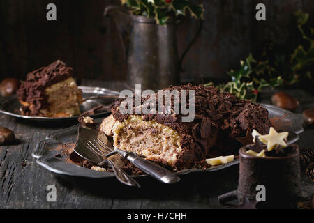 Des tranches de bûche de Noël aux châtaignes crème sur plaque vintage avec fourches, chocolat stars et holly branch Banque D'Images