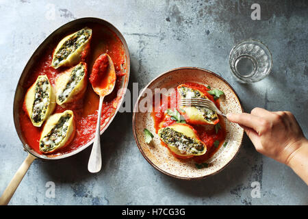 Manger des coquilles de pâtes farcies de fromage ricotta et épinards Banque D'Images