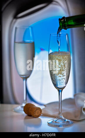 Première catégorie DE LUXE FLYING Pouring champagne français en vol en cabine de luxe avec fenêtre et l'aile derrière Banque D'Images