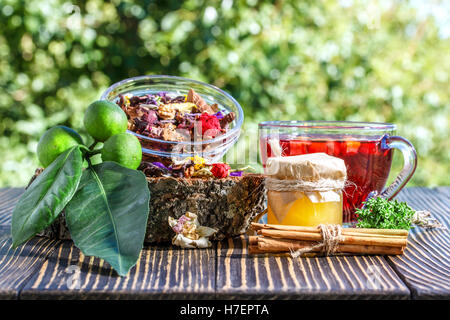 La tisane à la cannelle, fruits secs, miel et citron vert sur une table en bois à l'extérieur Banque D'Images