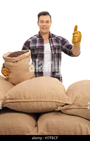 Travailleur agricole avec sacs de toile remplis de grains de café de donner un pouce vers le haut isolé sur fond blanc Banque D'Images