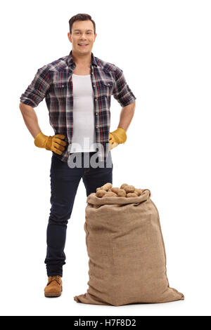 Portrait de jeune agriculteur debout derrière un sac de jute rempli de pommes de terre isolé sur fond blanc Banque D'Images