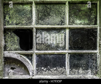 Une vieille fenêtre fissuré sur un bâtiment abandonné. Banque D'Images