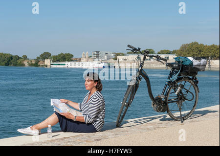 Cycliste féminine Claudia (Albrecht) reposant sur les berges du Rhône à Arles, Provence, France Banque D'Images