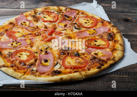 Pizza au bacon et tomates est sur une table en bois Banque D'Images