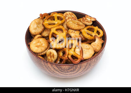 Mélange de snacks salés (crackers et bretzels) dans bol en bois isolé sur fond blanc Banque D'Images