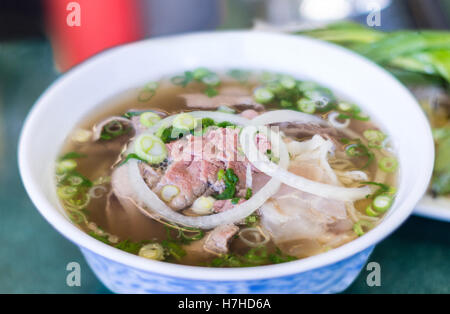 Bol de soupe de nouilles Pho vietnamien avec boeuf tendon, rares, tripes et poitrine servi avec des oignons et de la coriandre. Banque D'Images