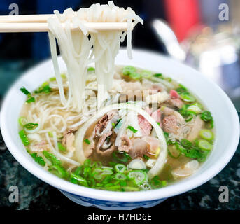 Bol de soupe de nouilles Pho vietnamien avec boeuf tendon, rares, tripes et poitrine servi avec des oignons, échalotes et la coriandre. Banque D'Images