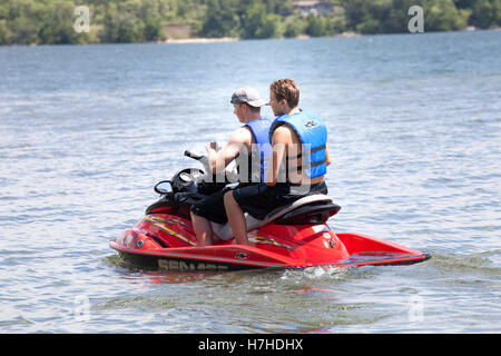 Deux adolescents portant des gilets de motomarines Sea-Doo conduite PWC sur le lac. Clitherall Minnesota MN USA Banque D'Images
