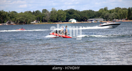 Bord de l'activité avec bateau de vitesse en tirant les enfants sur un tube d'eau alors que des adolescents passent sur un jet ski. Clitherall Minnesota MN USA Banque D'Images