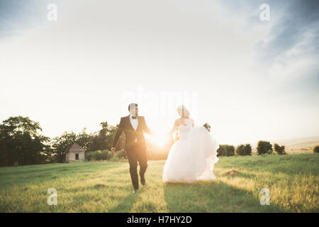 Couple de jeunes mariés heureux élégante promenade dans le parc le jour de leur mariage avec bouquet Banque D'Images