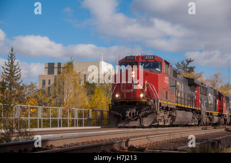 Train crossing bridge avec bleu ciel & nuages en arrière-plan (Brampton, Ontario, Canada). Banque D'Images