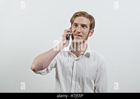 Jeune homme en chemise blanche adultes parle sur son téléphone Banque D'Images