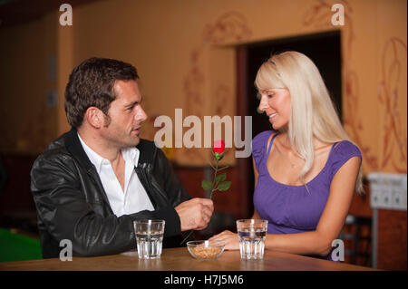 Ce jour, l'homme et la femme avec une rose rouge au bar Banque D'Images