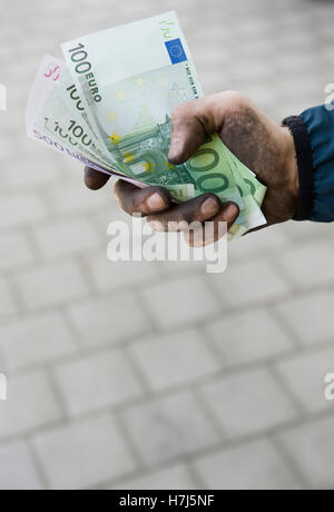 Image symbolique de l'argent noir, ouvrier manuel avec des mains sales holding banknotes Banque D'Images