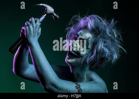 Femme blonde comme modèle de la fondrière, Fous, fous, clown meurtrier avec un marteau, violet éclairage rim Banque D'Images