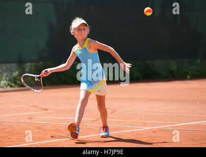 Girl jouer au tennis à un concours junior. Banque D'Images