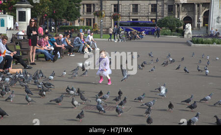 Les touristes et les habitants bénéficient de peu de fille jouant avec les pigeons dans George Square Banque D'Images