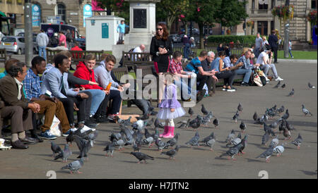 Les touristes et les habitants bénéficient de peu de fille jouant avec les pigeons dans George Square Banque D'Images