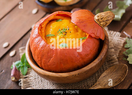 Crème de potiron soupe aux poivrons et aux fines herbes dans un potiron. Banque D'Images