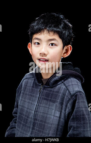 Bel asiatique Cute boy posing in studio sur fond noir avec effet rétro-éclairé. Banque D'Images