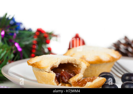 Partie mangé mince pie avec les bleuets et les décorations de Noël sur un fond blanc. Banque D'Images