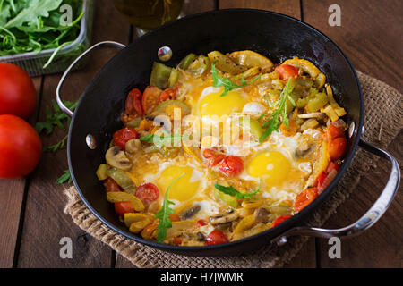 Oeufs au plat avec des légumes dans une poêle à fond de bois. Banque D'Images