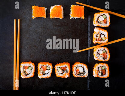 La cuisine japonaise traditionnelle - sushi, petits pains et baguettes pour sushi sur un fond sombre. Vue d'en haut Banque D'Images