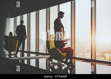 Jeune homme qui réussit à sourire entrepreneur officiel business suite pensivement debout près de fauteuil jaune Banque D'Images