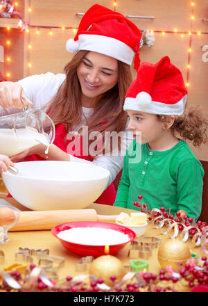 Happy Family prépare pour les fêtes de Noël, de la mère avec petit-fils porter du rouge Santa hats, faisant un des cookies au gingembre à la maison Banque D'Images