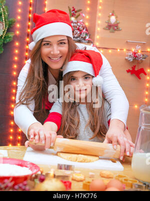 Happy Family making Christmas Cookies, mère et fille la pâte de moulage à la maison, préparation traditionnelle pour Noël Banque D'Images