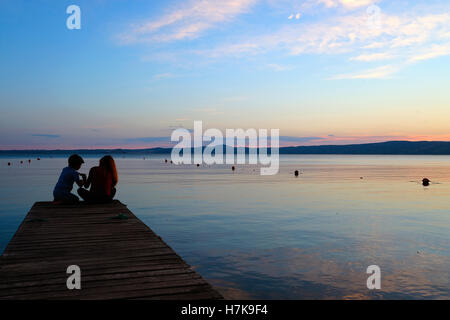 Deux enfants sur un quai au coucher du soleil sur le lac de Bolsena. Viterbo. Le Latium. Italie Banque D'Images