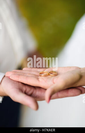 Close up of brode et la main tenant deux anneaux de mariage Banque D'Images