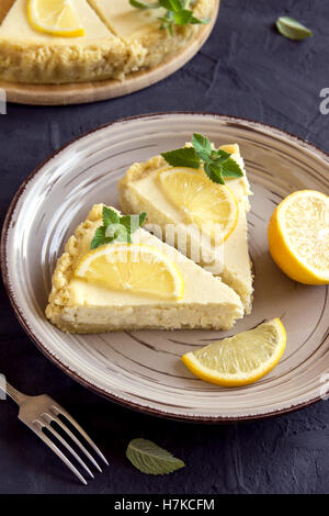 De délicieux morceaux de gâteau au fromage au citron fait maison avec des tranches de citron et de menthe sur la plaque close up Banque D'Images