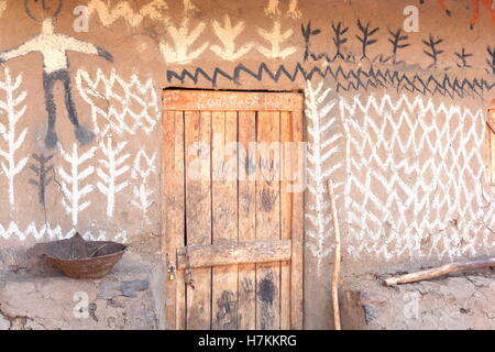 Porte en bois avec un cadenas sur le mur de boue peint naïvement d'un toit traditionnel en chaume maison du peuple Oromo. Hameau en Ethiopie Banque D'Images