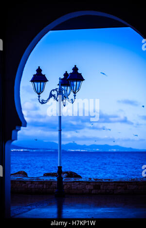 Vieille lampe de rue contre le coucher du soleil sur l'océan Banque D'Images