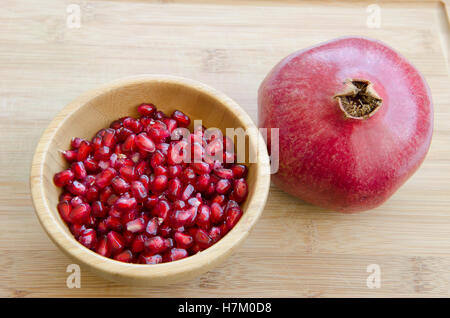 Fruits avec graines de grenade dans bol en bois on cutting board Banque D'Images