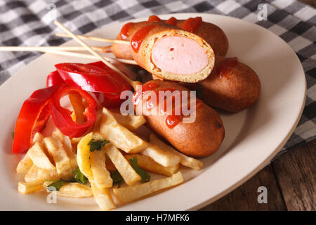 Chien de maïs, les frites et les légumes sur une assiette sur la table horizontale. Banque D'Images