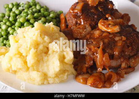 Salisbury steak avec une sauce aux champignons, purée de pommes de terre et les pois verts gros plan sur une plaque horizontale. Banque D'Images