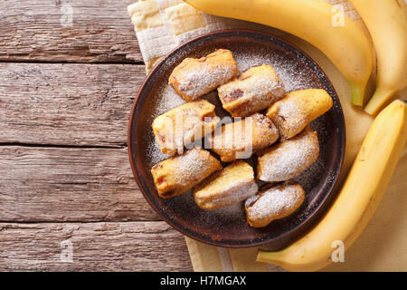 Bananes frites dans la pâte sur une plaque sur la table horizontale vue du dessus. Banque D'Images