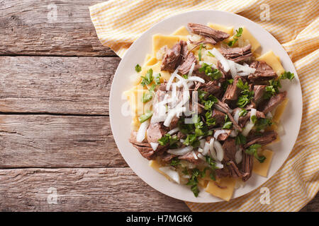 Plat de nouilles Beshbarmak : avec de l'agneau et l'oignon sur une assiette sur la table. Vue de dessus horizontale Banque D'Images