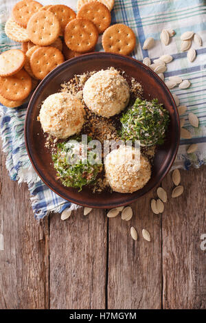 Boules de fromage de chèvre avec des craquelins, des herbes et graines de citrouille sur une assiette. vertical Vue de dessus Banque D'Images