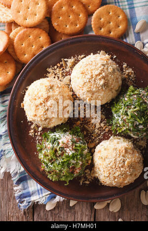 Des collations saines : boules de fromage avec des craquelins, des herbes et graines de citrouille close-up sur une assiette. vertical Vue de dessus Banque D'Images
