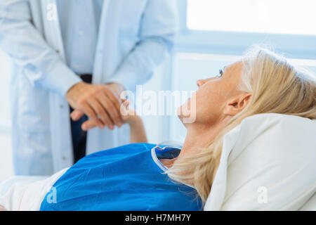 Doctor holding main du patient in hospital room Banque D'Images