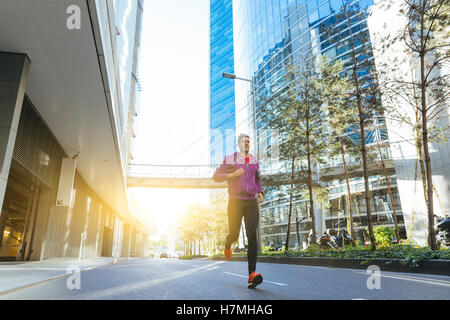 Écouteurs avec l'athlète s'exécutant dans la ville Banque D'Images