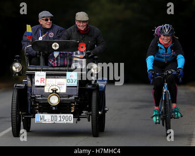 Les participants à l'Bonhams Londres à Brighton Veteran Car Run sont dépassés par un cycliste se rendant jusqu'Holmsted Hill près de Crawley, dans le Sussex. Banque D'Images