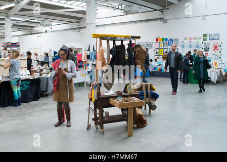 Jeune designer derrière un étal vendant des vêtements faits à la main à la Renegade Craft Fair, une manifestation annuelle du marché designer indépendant Banque D'Images