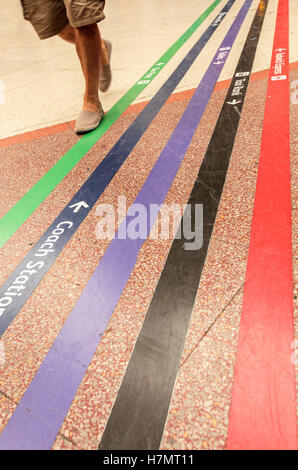 Passager unique de marcher le long des lignes colorées diriger les passagers vers différents points de la station tels que la table statio Banque D'Images