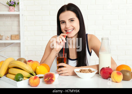 Il existe de belles femmes avec la peau pure sur son visage assis à une table et manger le petit déjeuner. Asian woman eating nourriture saine au petit-déjeuner. Des fruits, des céréales et du lait. Banque D'Images